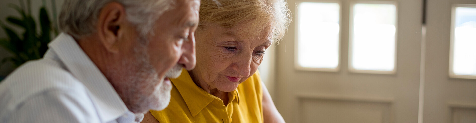 Älteres Paar prüft Vertrag mit einem Taschenrechner