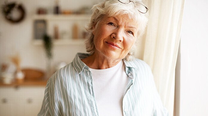 Ältere Frau hält Kaffeetasse in der Hand und lächelt
